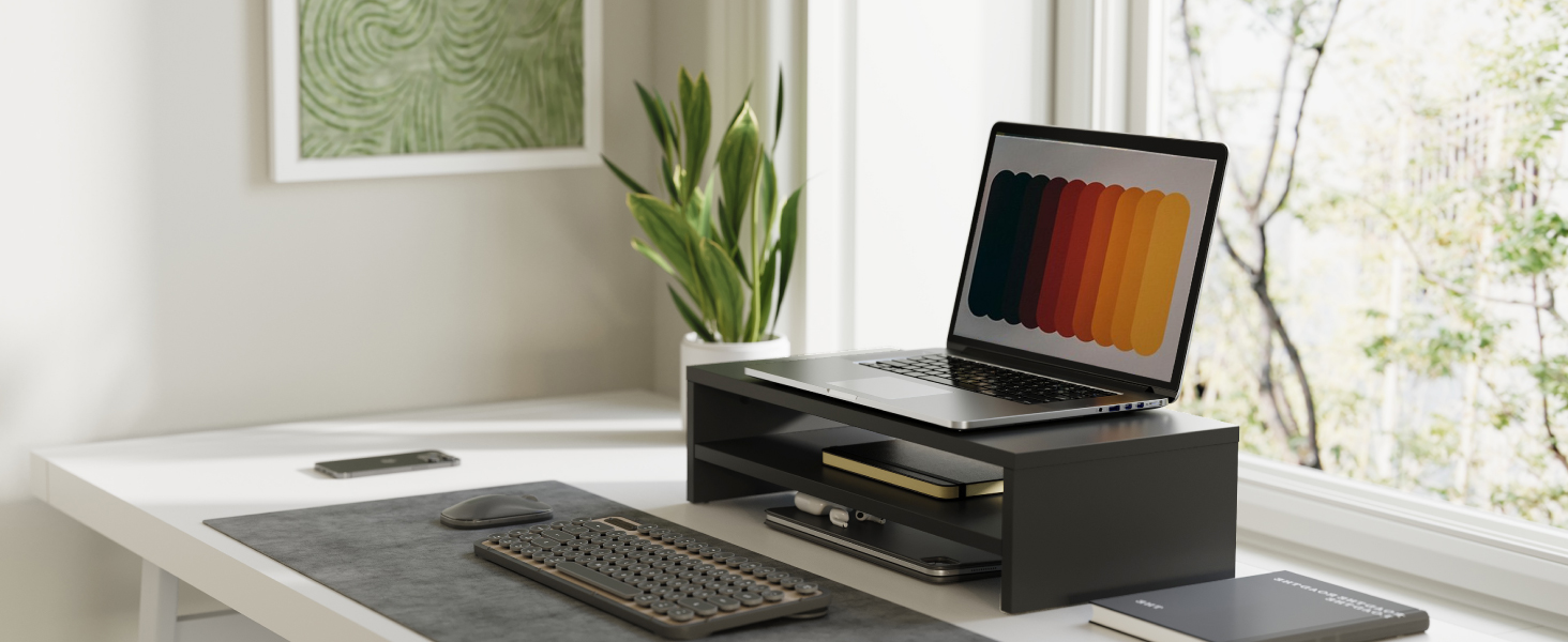 Interior workspace setup showing laptop on desk near window with natural lighting, office supplies, and modern minimalist decor.