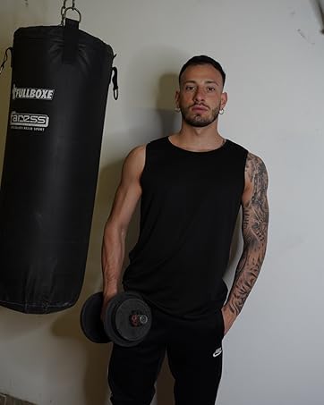 Fitness equipment in home gym setting: black punching bag hanging from ceiling and dumbbell on floor.