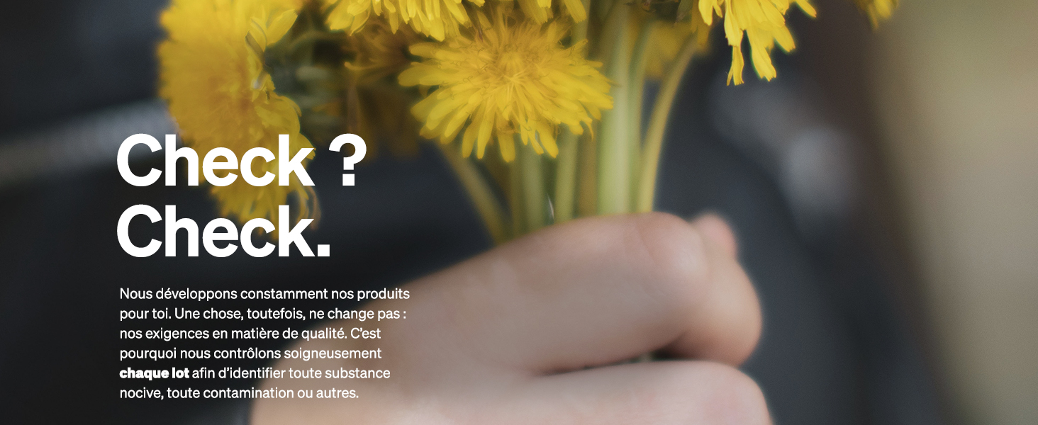 Des pissenlits jaunes au premier plan avec un texte flou « Check ? Vérifiez. 'visible. Main tenant un stylo en arrière-plan, suggérant un contexte d'écriture ou de prise de notes