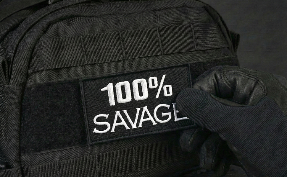 04-Close-up of a black tactical backpack with a Velcro-mounted embroidered patch reading 100% SAVAGE