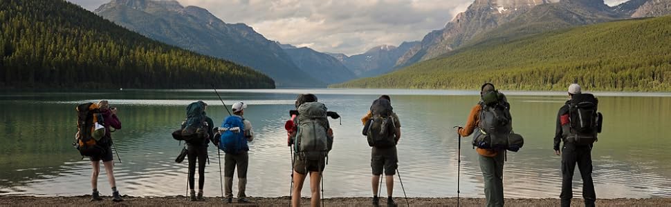 7 People in hiking gear in Montana look out onto a lake surrounded by Mountains