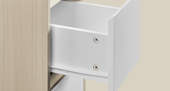 Detailný záber na zásuvku bielej skrinky s montážnym kovaním s dvoma viditeľnými skrutkami a mechanizmom posuvnej koľajnice.