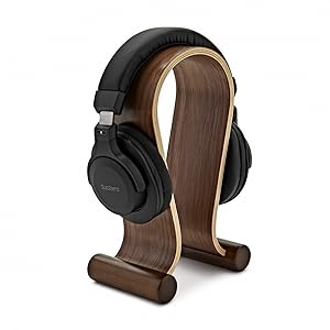 Black over-ear headphones displayed on a curved wooden stand with light wood accent trim.