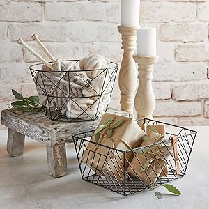 two wire baskets hold kniitting materials and wrapped packages beside two candlesticks on a table