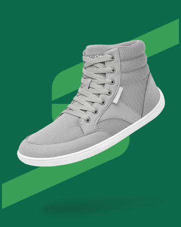 Zapatilla alta de color gris claro con suela blanca, exhibida sobre un fondo geométrico verde.