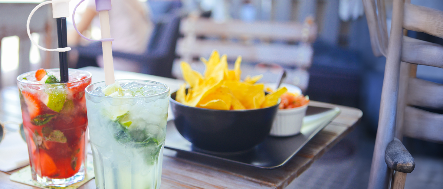 Two drinks on the table with cute straw covers on top of the straws to keep the dust out!