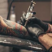 Tattoo artist tattooing on a man's arm