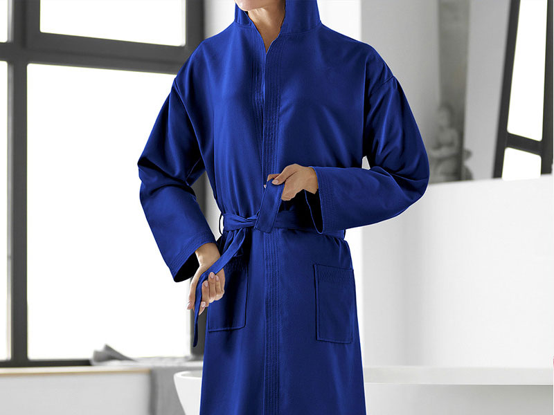 Vestaglia blu reale con zip frontale con maniche lunghe, colletto rialzato e cintura da annodare, mostrata in mostra sullo