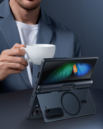 Tablet device in a dark stand case displaying colorful screen graphics, positioned on table while coffee cup visible in background.