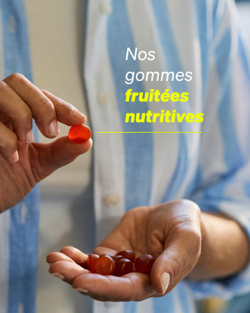 Main tenant un seul bonbon rouge et plusieurs autres dans la paume. Le texte superposé indique « Nos gommes fruitées