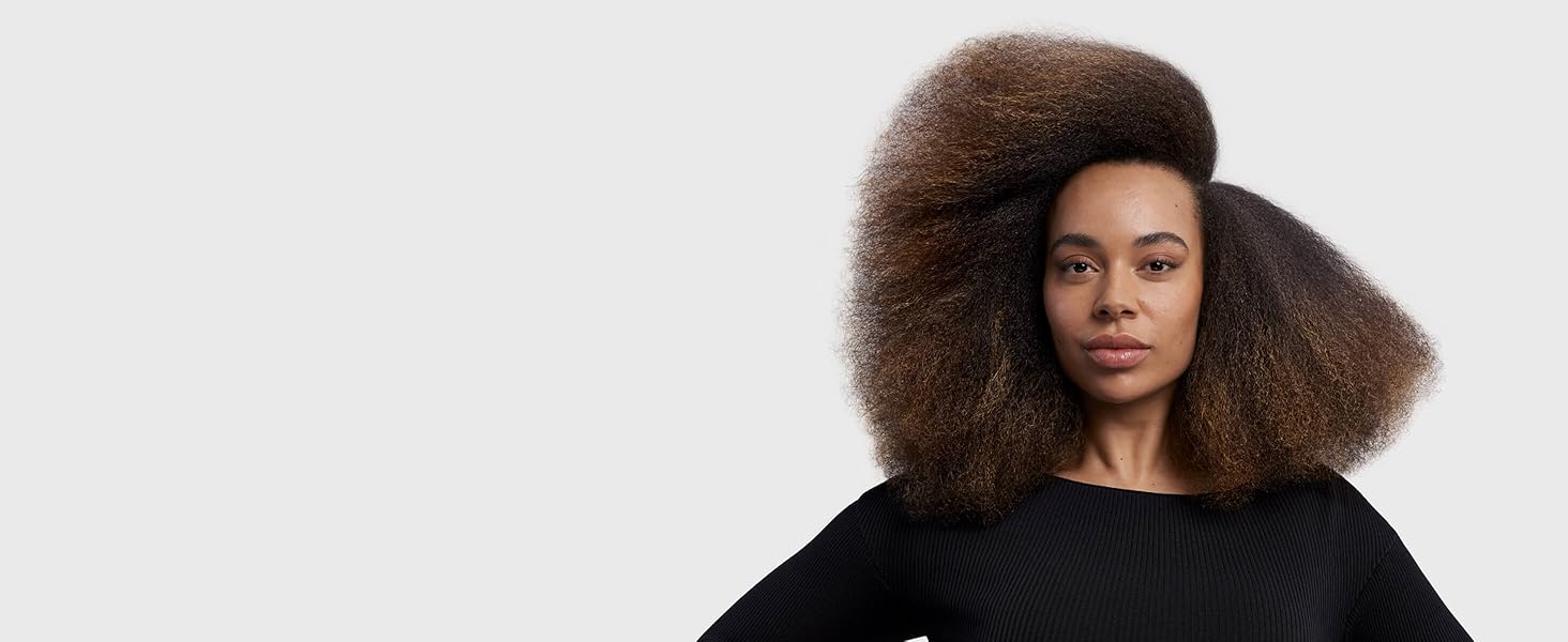 A brunette model with coily hair in a sweeping stretched blowout style.