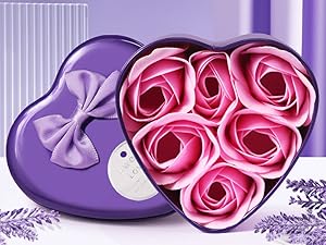 Violette herzförmige Schachtel mit dekorativer Schleife, die fünf rosa Seifenrosen enthält, die in einem Blumenmuster auf lavendelfarbenem Hintergrund angeordnet