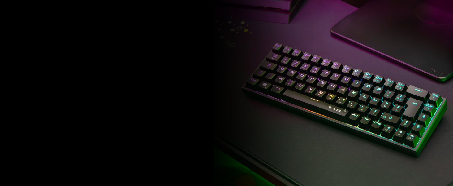 Clavier mécanique compact avec touches rétroéclairées RGB, affiché en basse lumière avec éclairage ambiant vert et violet