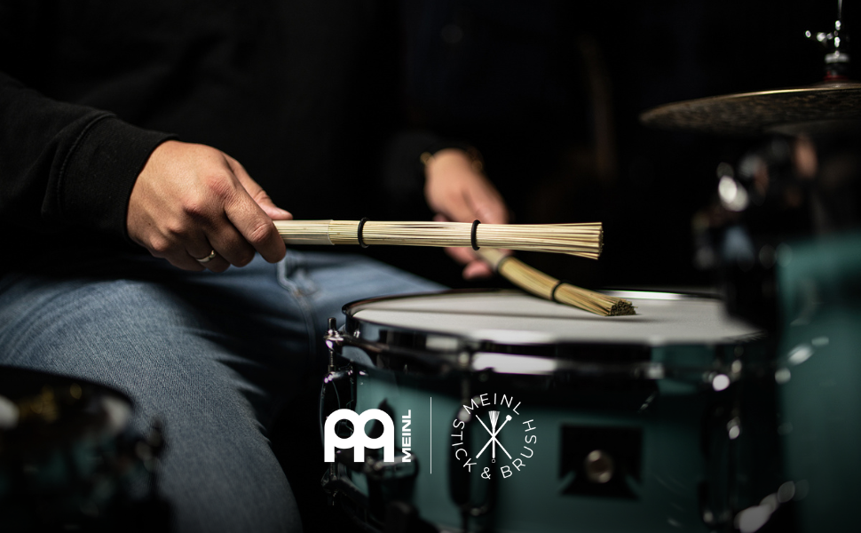 player using husk brushes on drum kit