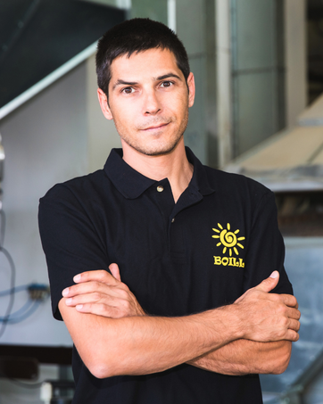 Professioneller Mitarbeiter trägt schwarzes Poloshirt mit gesticktem Sonnenlogo im Geschäftsumfeld.