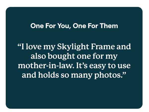 Skylight digital photo frame on table, with hand holding phone.