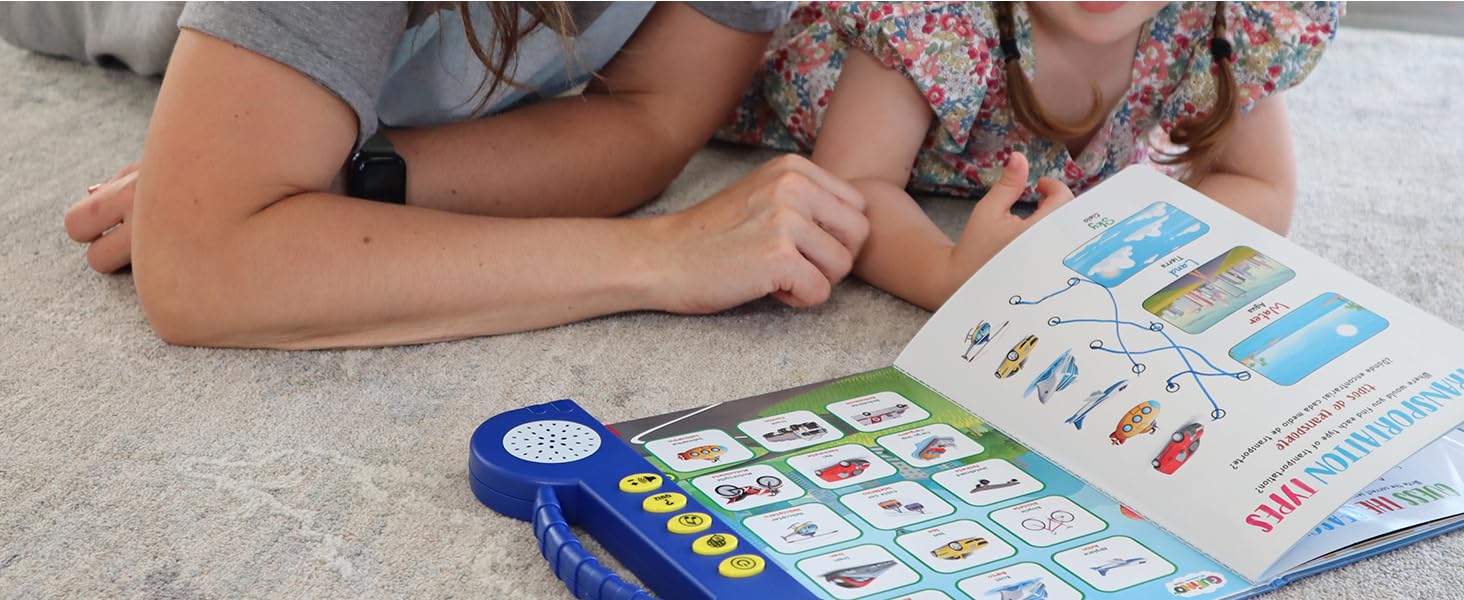 A parent and a child laying down on the floor and reading a bilingual electronic learning book