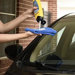 person squeezing Rain-X X-treme clean onto microfibre cloth infront of car