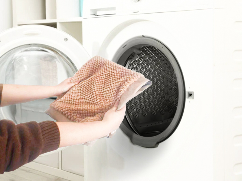 eine Person, die ein Tuch in eine Waschmaschine legt.