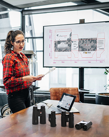 una mujer de pie frente a una mesa con una pizarra blanca que muestra la pantalla de un proyector