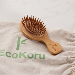 Cepillo de madera de bambú con cerdas redondas sobre tela de color claro con texto visible.