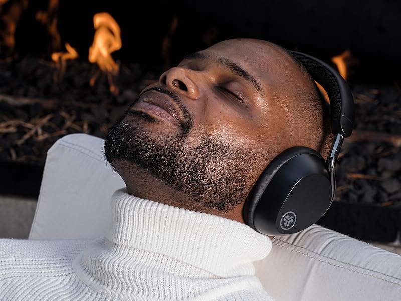 Relaxing and reclining next to a fireplace while wearing jlab epic lux anc