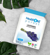 A white bottle of HealthKart Lavender capsules on a white surface, surrounded by green leaves. The product label shows lavender flowers and highlights 'Calm & Relax'.