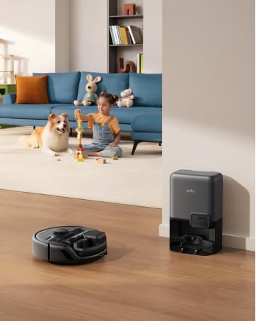 Roboterstaubsauger auf Hartholzboden neben seiner Ladestation. Blaue Couch, spielendes Kind und Hund im Hintergrund sichtbar