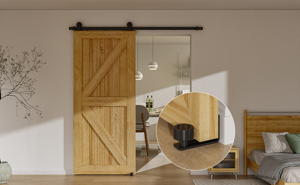 Scheunentor aus Holz auf Schiebebahn. Die Nahaufnahme zeigt die schwarze Bodenführung. Die Tür führt zum Küchenbereich. Blick auf das Schlafzimmer mit sichtbarem Bett und Pflanze