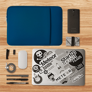Flat lay of electronic accessories including blue laptop sleeve, smartphone, mouse, and various cables on a wooden surface. Laptop displays tech company stickers.
