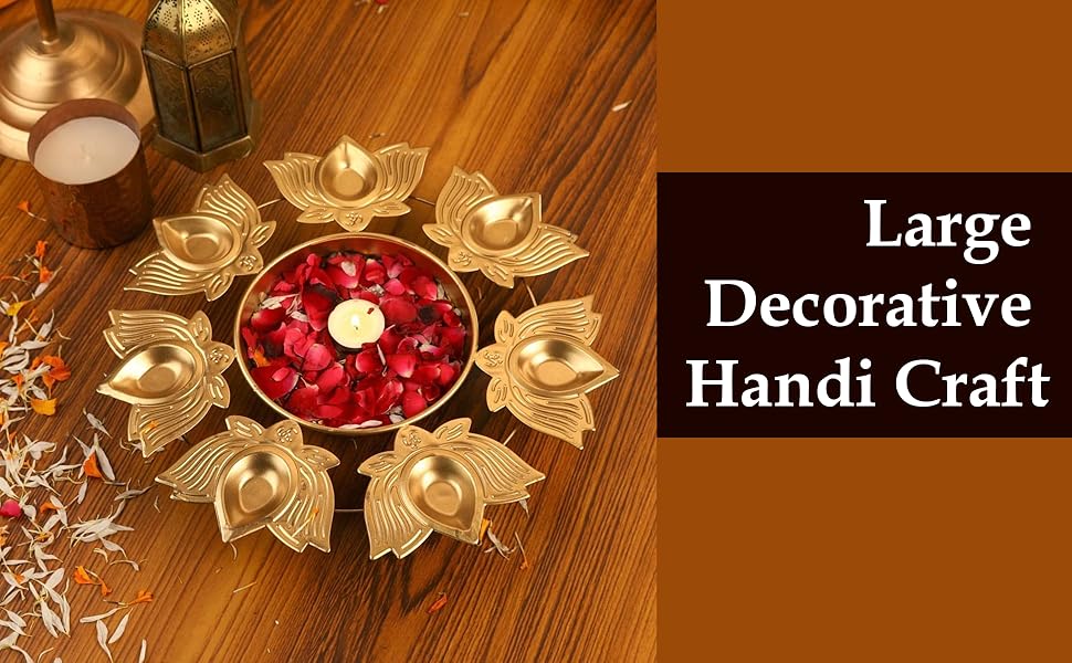 Large decorative golden metal dish with lotus-like design, holding red rose petals and a lit candle in the center.