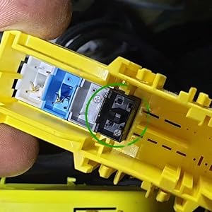 Primer plano del interior amarillo de una herramienta de red o pelacables, que muestra las conexiones de los cables expuestas y los componentes codificados por colores
