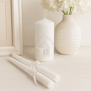 white candles on a home surface with vase and frame