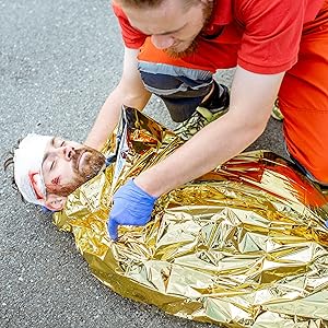 O persoană rănită este înfășurată în pătura de salvare Livaia, partea de aur în sus