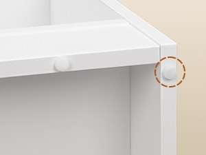 Nahaufnahme einer weißen Schrankecke mit einem kleinen, kreisförmigen selbstklebenden Sicherheitsschloss am Rand, das Schränke und Schubladen kindersicher machen soll