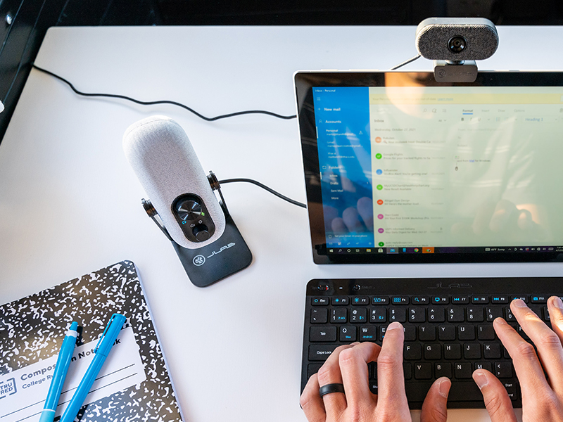 go talk mic next to hand typing on keyboard on a white desk