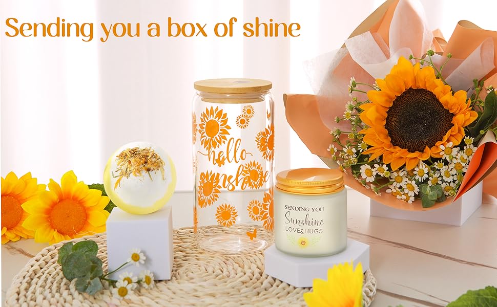 Geschenkarrangement mit dekorativen Glasgefäßen mit Sonnenblumenmuster, begleitet von frischen Sonnenblumen und Babyatem auf gewebter Oberfläche