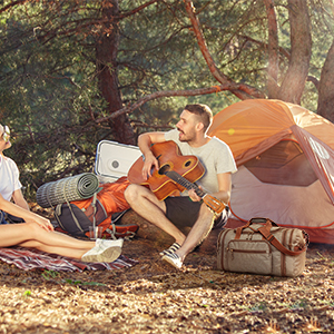 Person playing Guitar while the travel Duffel has accommodated all his camping and travel needs