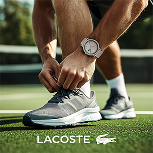El texto dice «LACOSTE». Las zapatillas deportivas se muestran en acción sobre hierba, centrándose en el calzado durante el movimiento o la actividad deportiva.