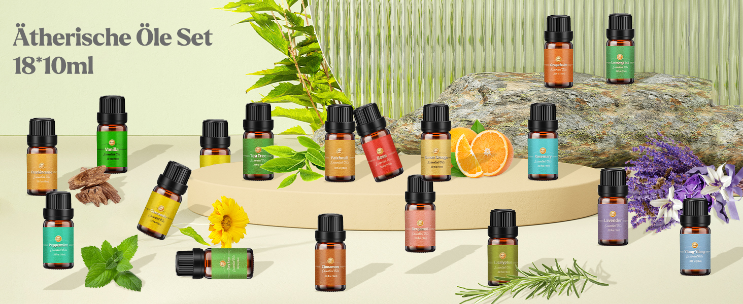 Set mit 18 Flaschen mit ätherischen Ölen, jeweils 10 ml, präsentiert mit verschiedenen Kräutern, Blumen und Zitrusfrüchten. Die Flaschen sind mit verschiedenfarbigen Etiketten versehen, die den Ölsorten entsprechen