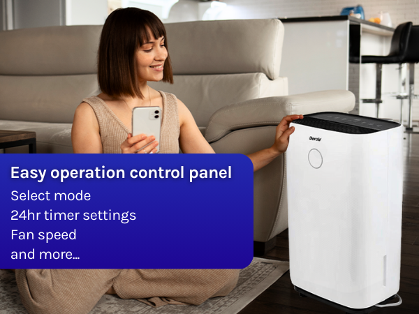 White rectangular air purifier with control panel, featuring easy operation, 24hr timer, fan speed settings, and mode selection. Woman using smartphone nearby.