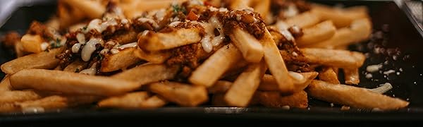 A plate of golden french fries topped with a dark, meaty sauce and grated cheese. The fries are piled high on a dark plate or surface.