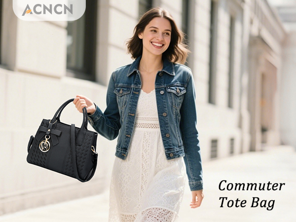 Black structured commuter tote bag with leather-look finish, multiple compartments, and metal hardware detailing, shown in outdoor setting.