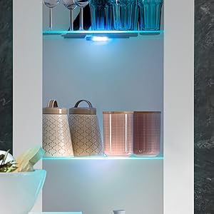 Beleuchtete Glasregale mit blauer LED-Beleuchtung, auf denen dekorative Aufbewahrungsbehälter in metallischer und gemusterter