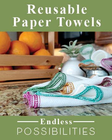 Stack of colorful reusable paper towels on kitchen counter with fruit bowl in background.