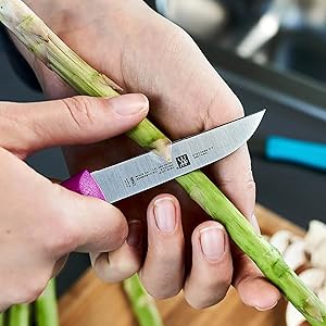 Person peeling asparagus with a knife.