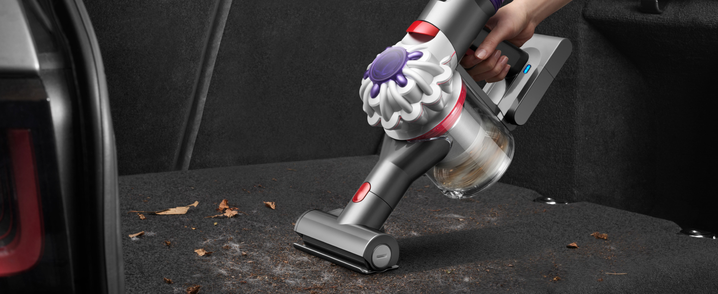 Dyson Car+Boat handheld vacuum cleaner removing dirt and hair from a car boot.