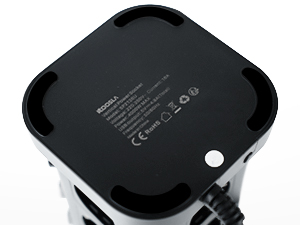 Vue du dessous d'un appareil électronique carré noir ou d'une base montrant les informations réglementaires et les marquages sur fond blanc.