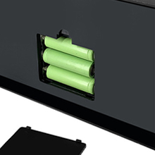 Tres baterías cilíndricas de color verde visibles a través de un dispositivo rectangular negro con un compartimento abierto.