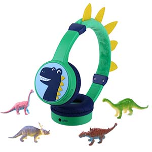 Green and blue children's headphones with decorative dinosaur spikes on top, shown with small toy dinosaur figures including T-Rex and other species.